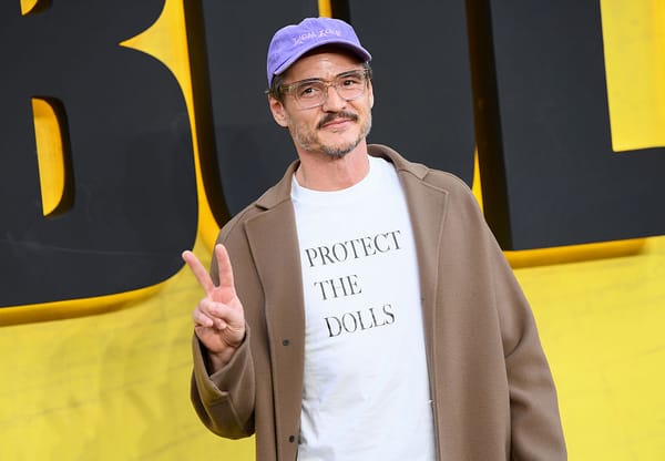 Pedro Pascal wearing a white t-shirt with the text "protect the dolls" in all caps.